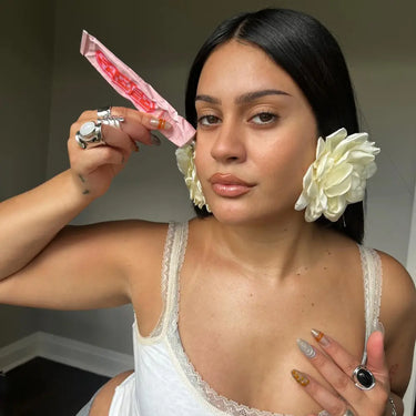 Serum for hyperpigmentation held by a woman with bold accessories and flowers in her hair
