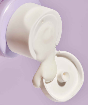 Topicals Faded Dark Spot Serum for Face spilling from an open tube against a pastel purple background.